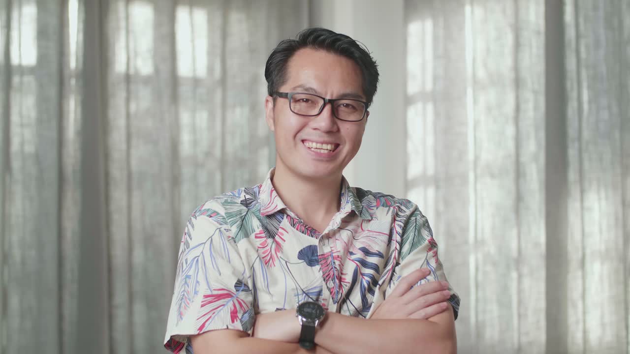 카드보드 상자를 들고 있는 아시아인 남자가 미소 짓고 새 집에서 카메라를 향해 팔을 고 있다.