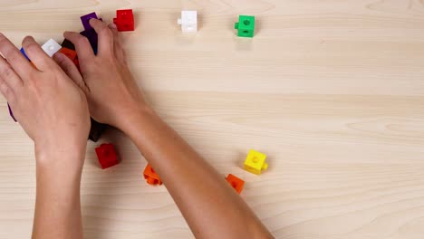 hands collaborate to organize colorful linking cubes