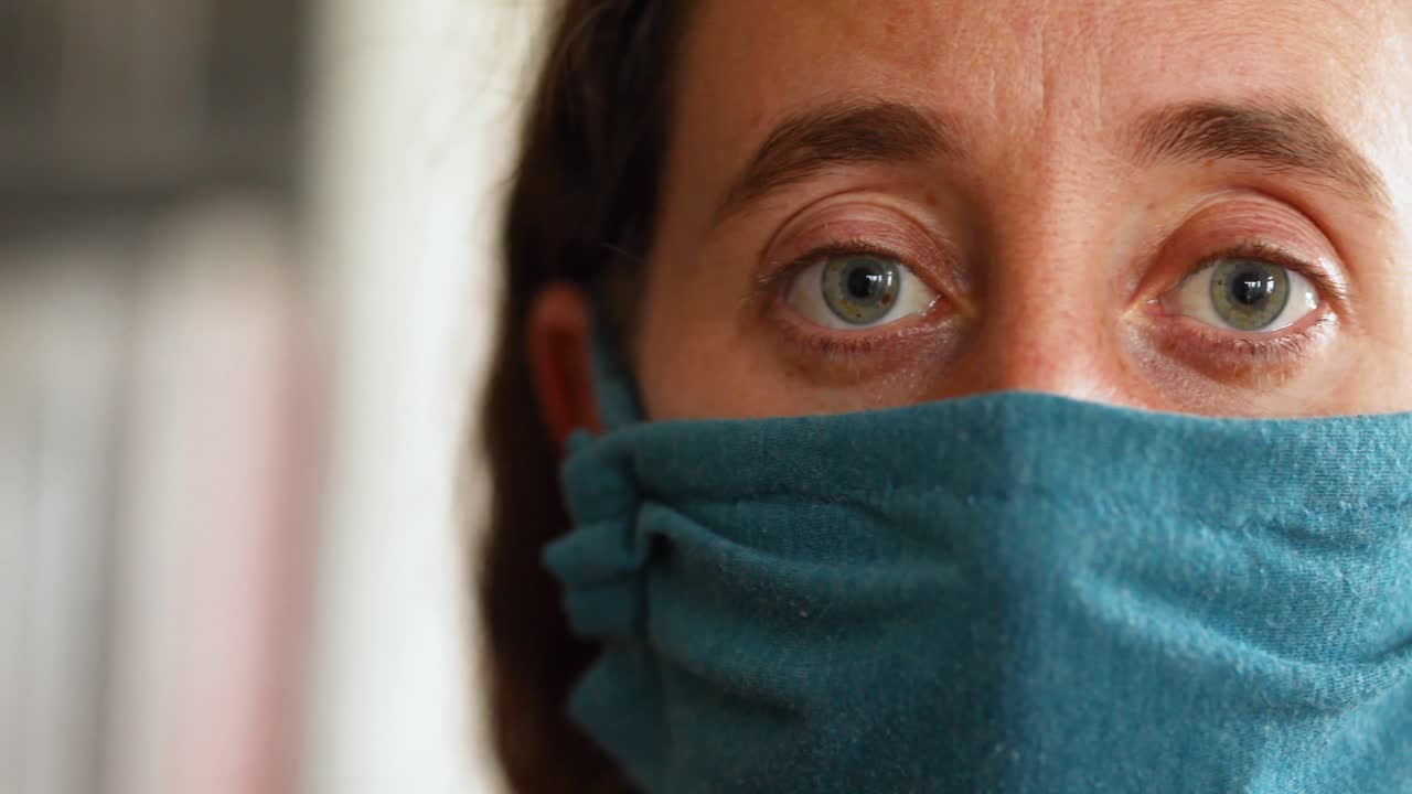 donna caucasica che indossa una maschera facciale a casa