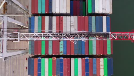 Drohnenaufnahme-Aus-Der-Luft-Von-Oben-Nach-Unten,-Die-über-Containerschiffe-Fliegt,-Kippt-Nach-Oben,-Um-Container-Im-Hafen-Zu-Entladen