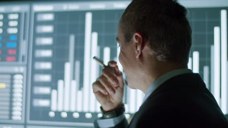 hombre de negocios alegre mirando un gran monitor digital con datos y pensando