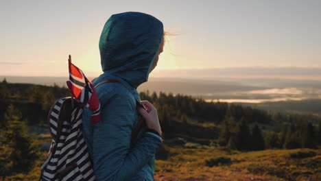 A-Tourist-With-A-Norwegian-Flag-In-A-Backpack-Walks-Through-The-Picturesque-Highlands-At-Dawn-Active