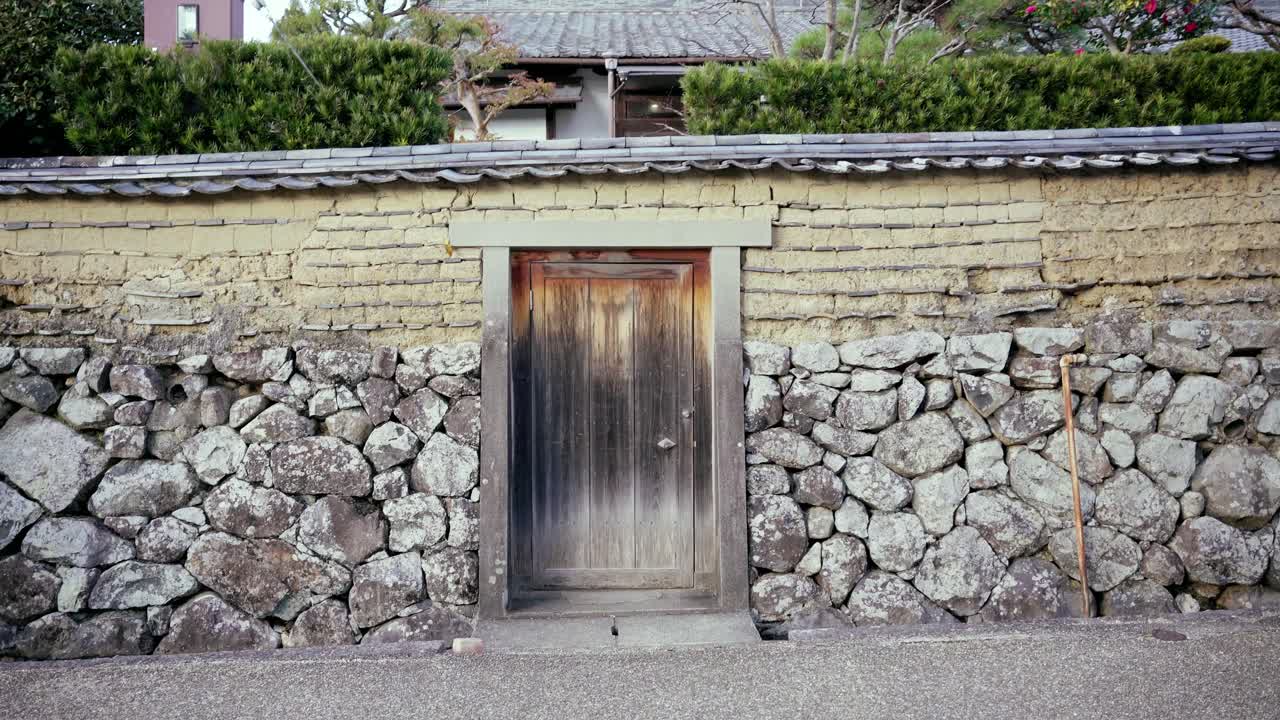 A mother walks past an old door with a stroller in Nara, Japan