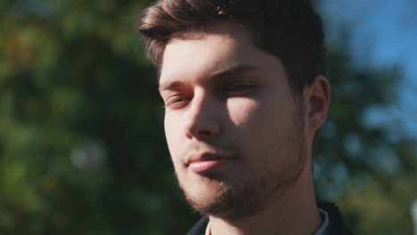 portrait of young handsome man smiling and looking at camera outdoors