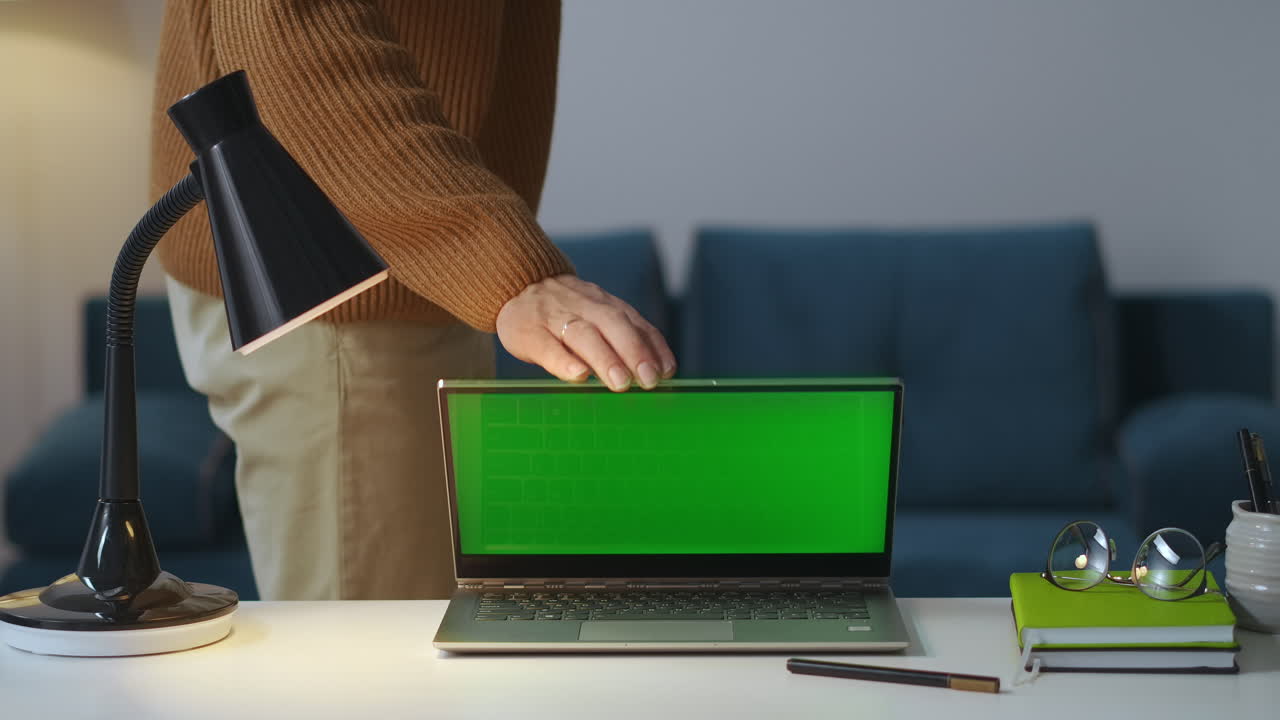 el hombre está cerrando la computadora portátil con pantalla verde en la habitación por la noche y apagando la lámpara terminada vista de trabajo en la mesa de trabajo de freelancer o escritor oficina en casa