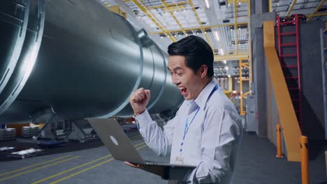 ingeniero celebrando el éxito con una computadora portátil en la fábrica