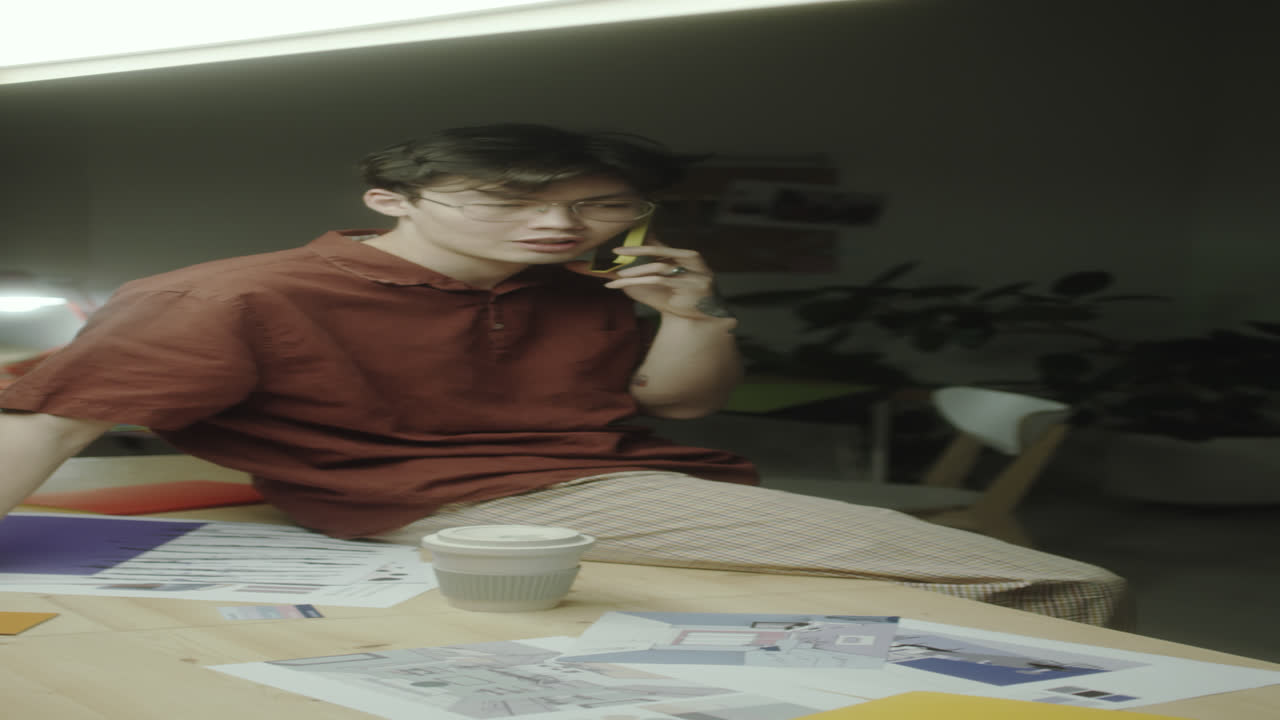 Asian Designer Chatting on Phone in Night Office