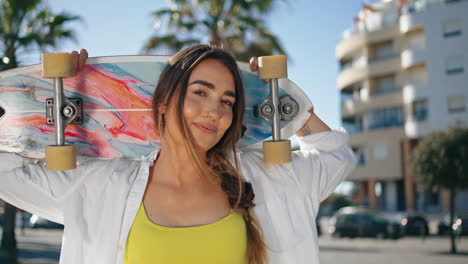 patinadora positiva chica mirando cámara retrato de ciudad tropical. mujer sosteniendo patín