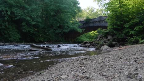 el agua fluye sobre piedras cerca del puente de conducción prohibido en wissahickon creek