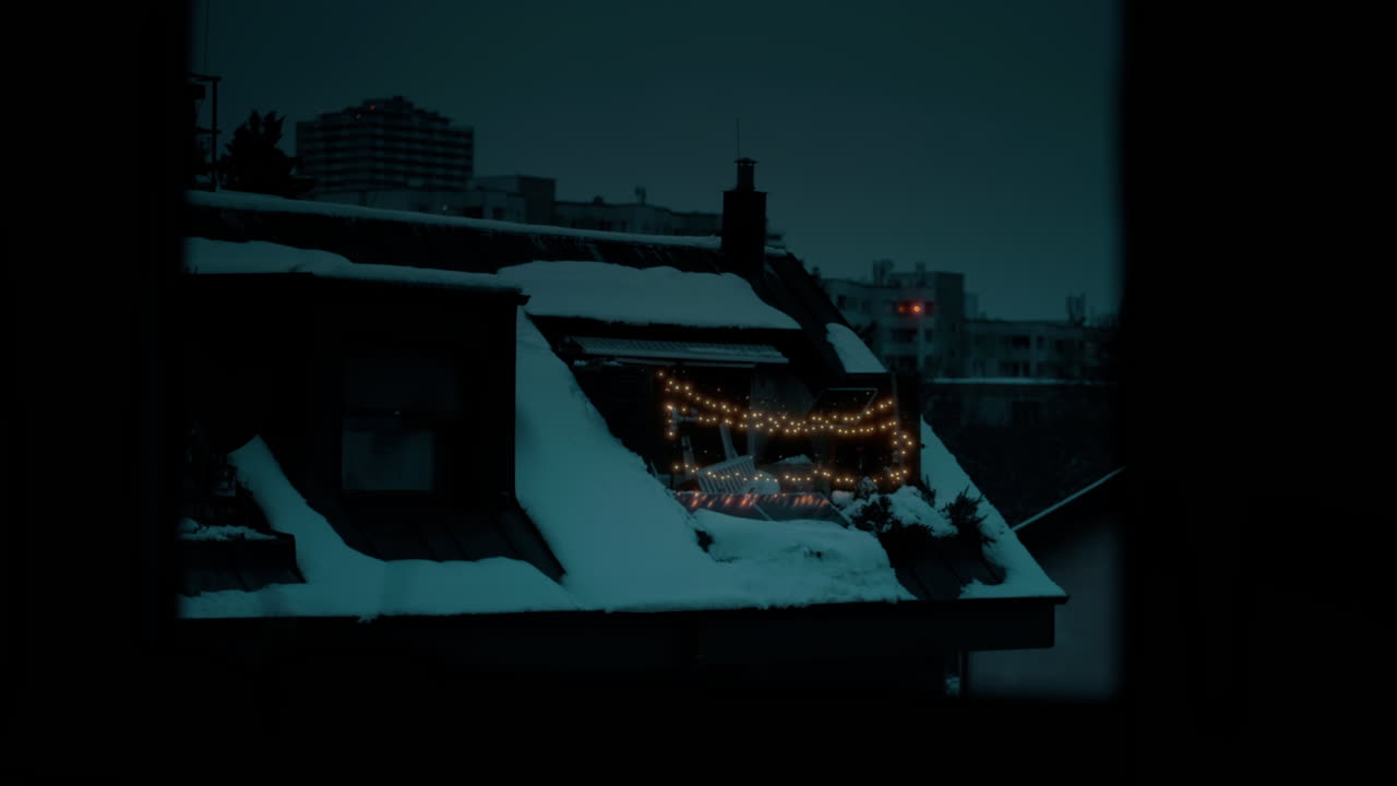 toma cinematográfica de una casa cubierta de nieve con luces de navidad brillando durante una noche