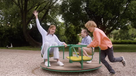 una niña con síndrome de down jugando con sus amigos en el parque en un día ventoso. están girando en un carrusel