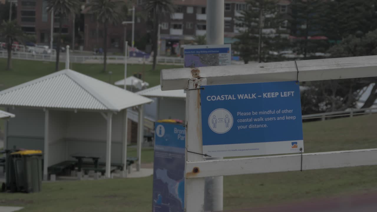 coche blanco pasando por el paseo costero con señal de distanciamiento social - paseo costero de la playa de bronte durante covid-19 - sydney, nsw, australia