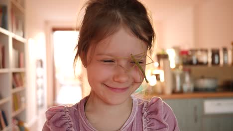 el retrato de una niña linda sostiene una mascota de insecto en las manos y se la pone en la cara en casa divertirse y sonreír