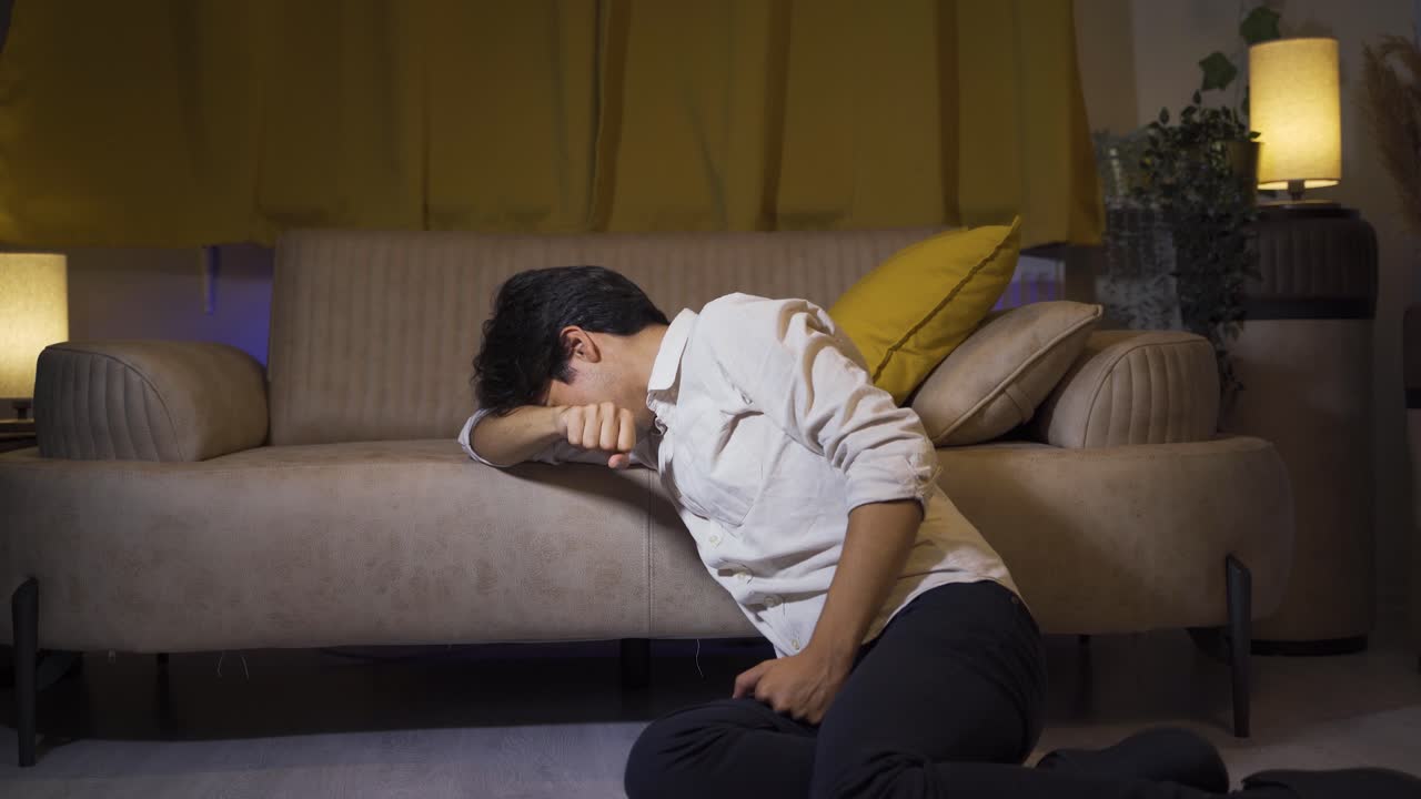 소파에 누워 있는 남자가 울고 있다.