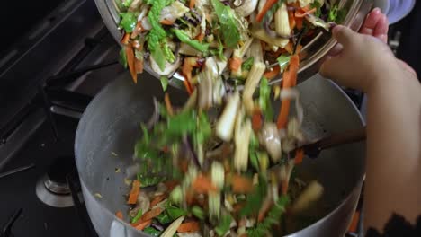 cooking chef adding vegetable stir-fry in pot with onions