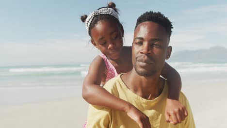 African-american-daughter-hugging-her-father-from-behind-at-the-beach