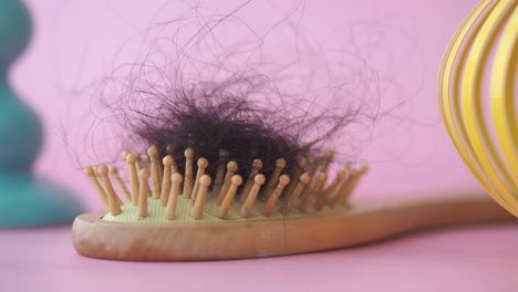 hair loss on a wooden brush against a pink background