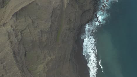 drone top down shot of waves bounce on rocks at the coast