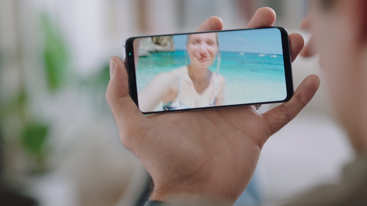 joven chateando por video usando un teléfono inteligente con su novia en una playa de vacaciones en italia compartiendo experiencia de viaje divirtiéndose en vacaciones chateando con un teléfono móvil 4k