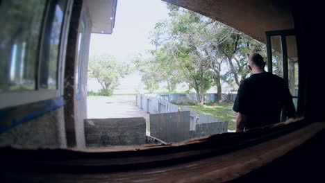 slow motion - view from inside a house looking outside at a bald man leaving the home