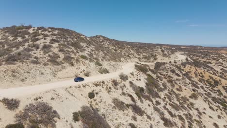 aerial: rental car driving on dirt track road in desert, off-grid exploration