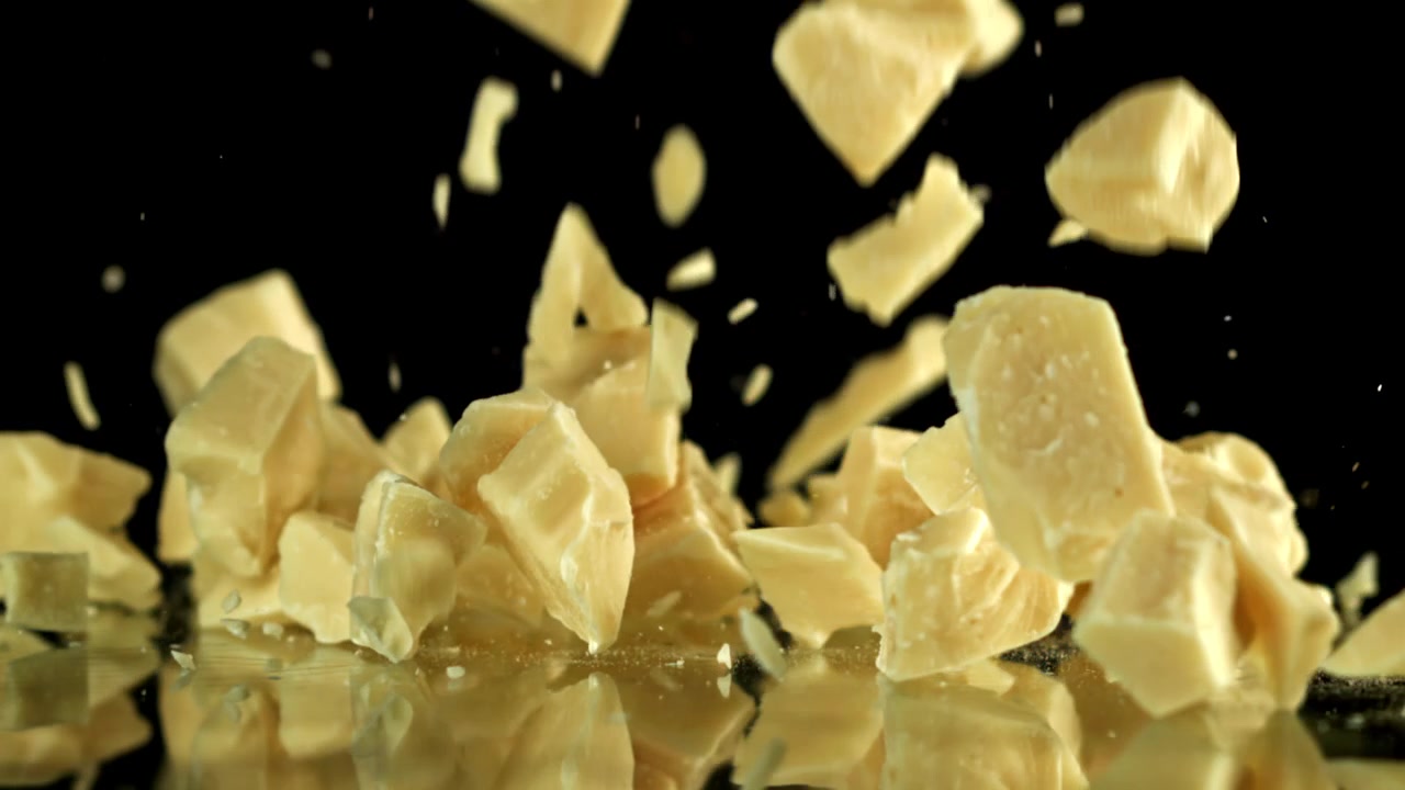 White Chocolate Pieces Falling in Slow Motion on Black Background