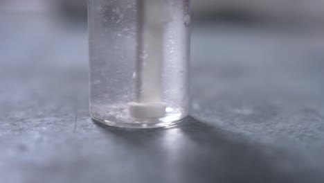 a water treatment tablet is put in the water of a small glass flask and is dissolving after being broken up by a small pestle