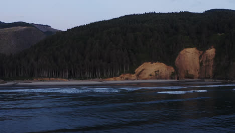 Suaves-Olas-Rodando-En-La-Remota-Playa-De-La-Costa-De-Oregon-Bordeada-Por-Un-Bosque-Siempre-Verde