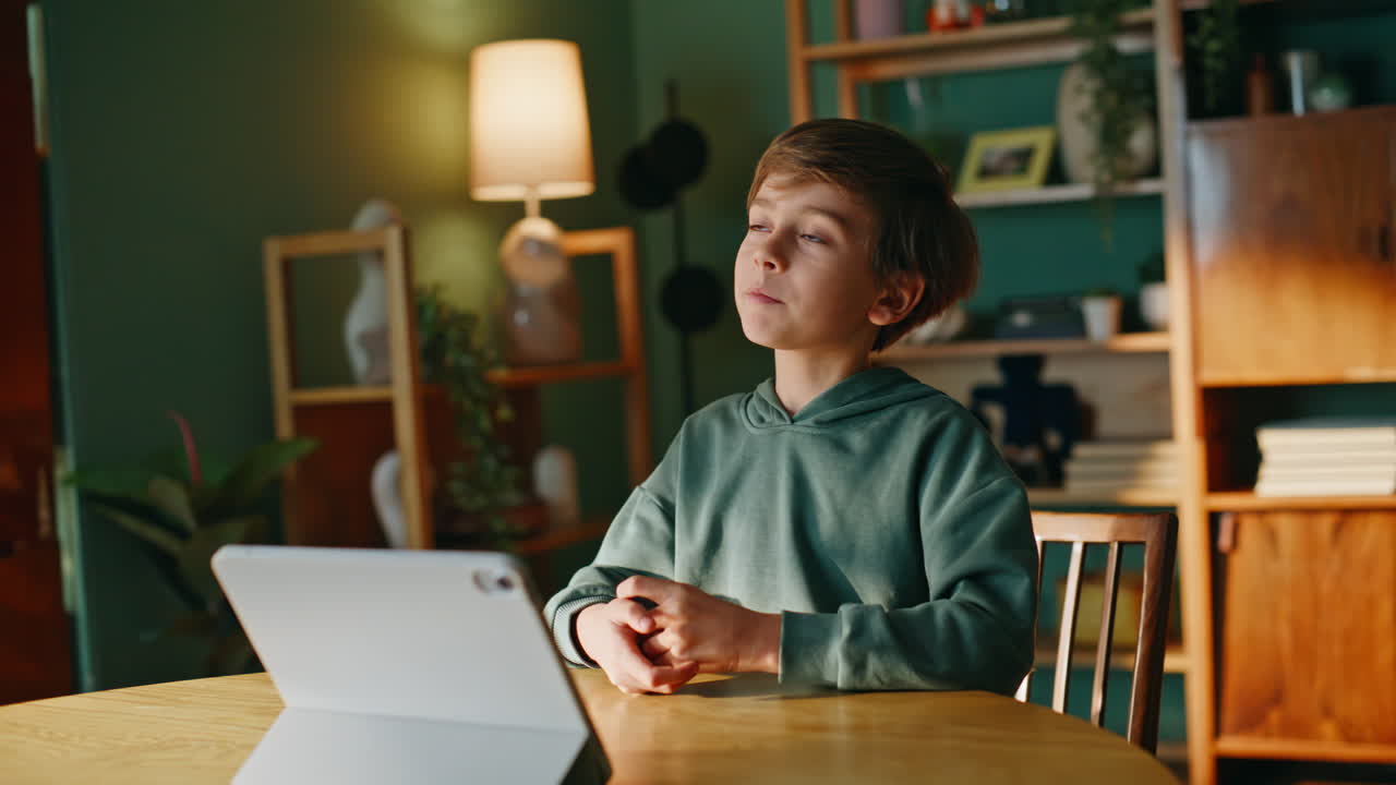 Boy talking online meeting looking tablet web camera sitting home desk closeup