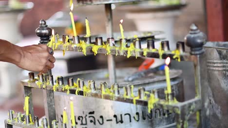 person lighting a candle at a shrine