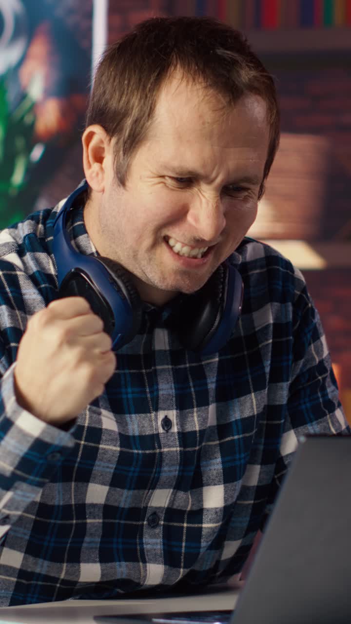 Vertical video Man enjoying leisure time at home, texting friends on laptop