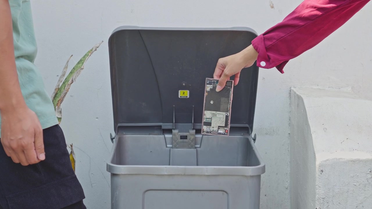 People throwing broken smartphone screens and circuit boards into dedicated e-waste bin