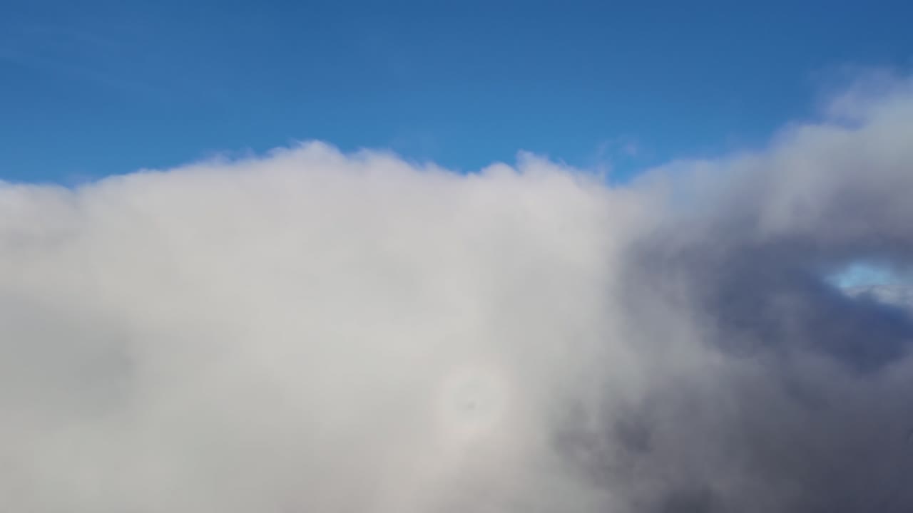 Immersive pilot’s view from the cockpit of a jet airplane, with a view of the halo of the plane (Anthelion) during the cloud immersion