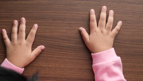 las manos del niño en la mesa de madera