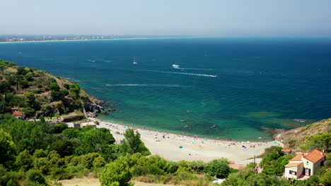 Aerial-shot-of-a-beach-with-people-near-Collioure-at-the-Mediterranean-Sea-during-a-hot-summer-day