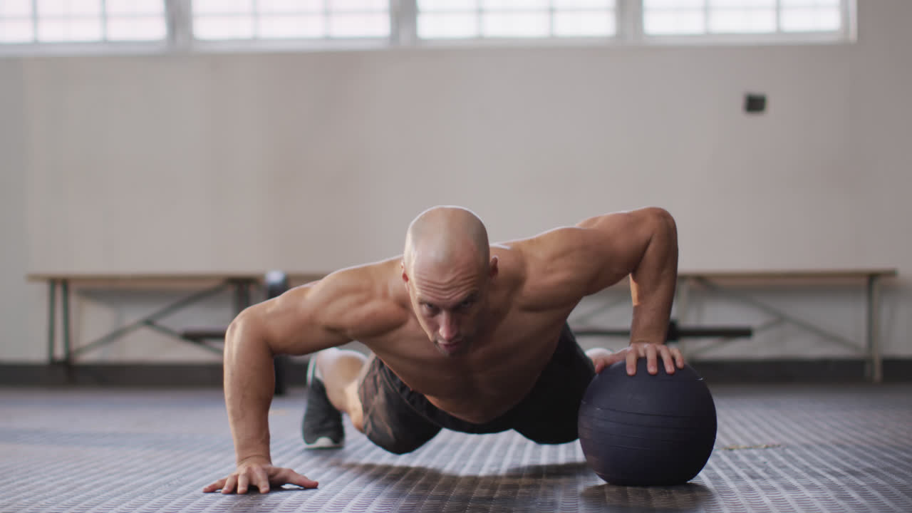 hombre caucásico en forma trabajando con la pelota de medicina en el gimnasio