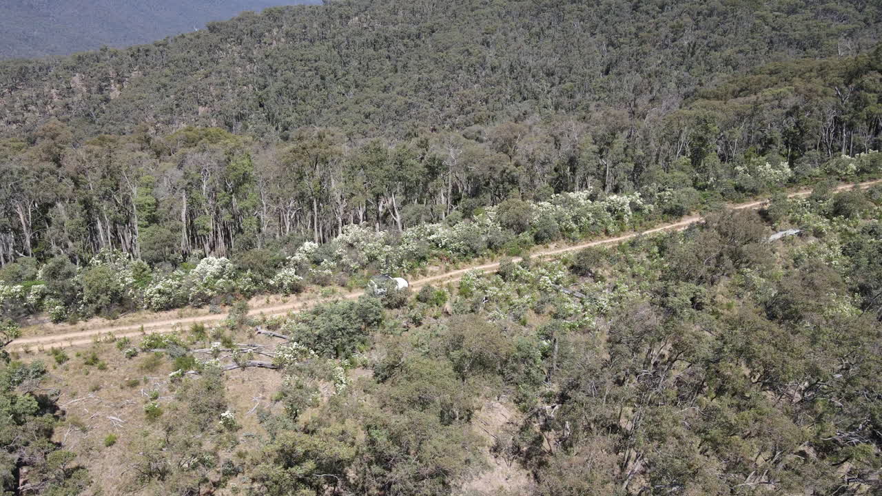 vista lateral de un dron aéreo después de conducir en 4x4 por un camino de tierra hasta una montaña en los matorrales cerca del lago eildon victoria australia