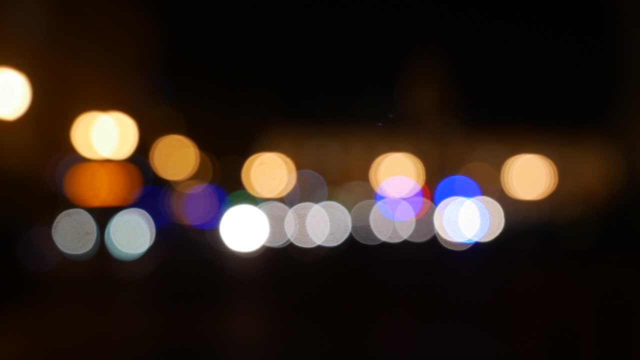hermoso bokeh brillante en el fondo oscuro borroso por la noche. el redondo bokeh colorido brilla de las luces de los coches en la calle de la ciudad. fuera de foco con borroso. luces de la ciudad sin enfoque. bokeh de tráfico. concepto abstracto