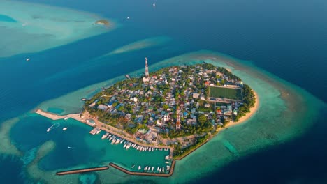 a stunning aerial drone view showcasing rasdhoo island surrounded by crystal-clear turquoise waters and vibrant coral reefs in the maldives.