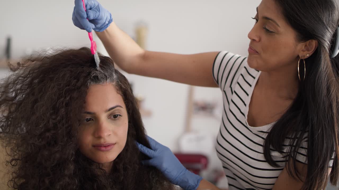 Video of two hairdresser coloring a woman's hair at home