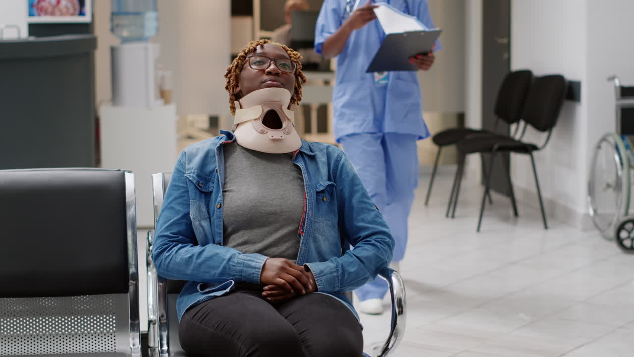 Patient with Neck Brace Assisted by Nurse in Hospital Waiting Room