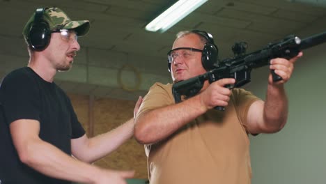 un hombre aprende a disparar un rifle en el campo de tiro. el instructor muestra al aprendiz la posición correcta de tiro