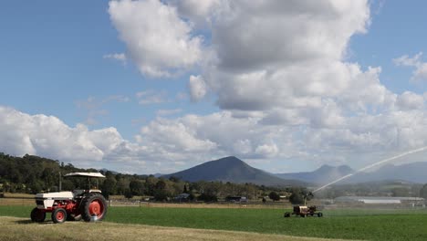 red tractor actively plowing through a scenic field