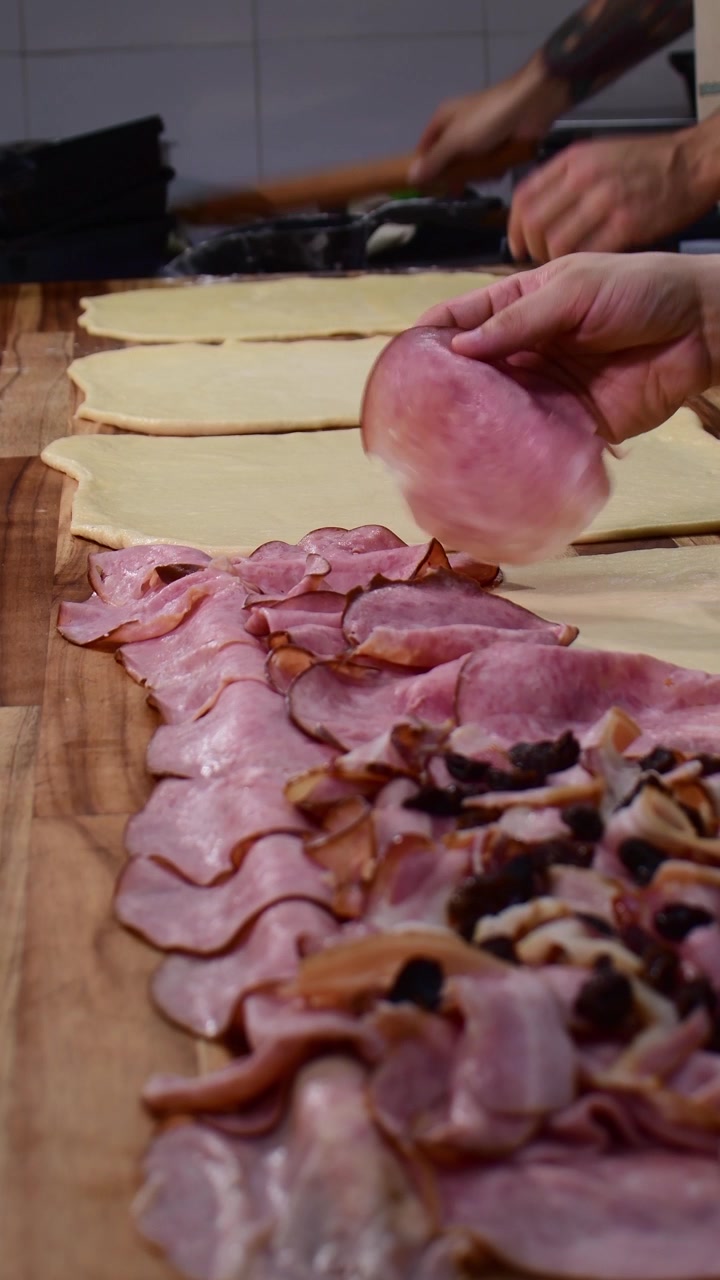 Primo piano verticale di mani che mettono il prosciutto sull'impasto per il pan de jamon.