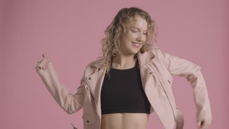 foto de estudio de una joven que se divierte bailando contra un fondo rosa 1