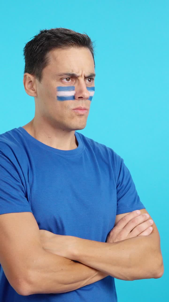 Homem com a bandeira salvadorenha pintada, olhando para o lado com expressão séria