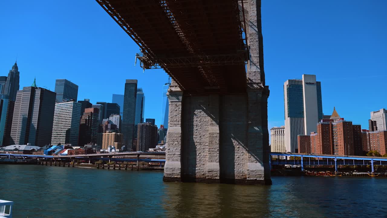 New York, USA, 5 ottobre 2025: Veduta dello skyline di Manhattan da sotto la struttura del Ponte di Brooklyn. Vista dal basso del fiume e dei grattacieli incorniciati dalla pietra e dall'acciaio di un ponte