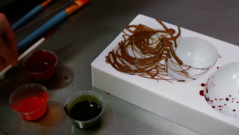 worker painting a chocolate mould using colored chocolate