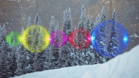 animation of snow falling and christmas baubles over winter fir trees