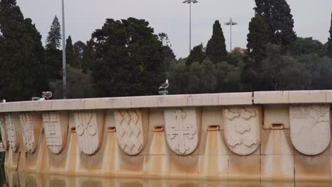 birds on top of historical fountain with trees in background